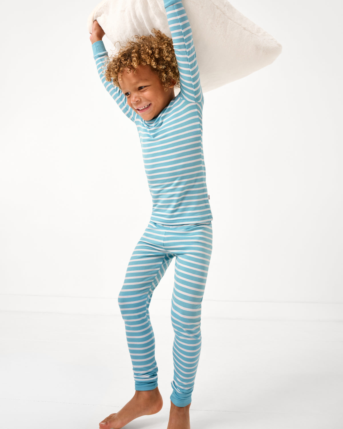 Boy playing with a pillow wearing the Dockside Stripe Two-Piece Pajama Set