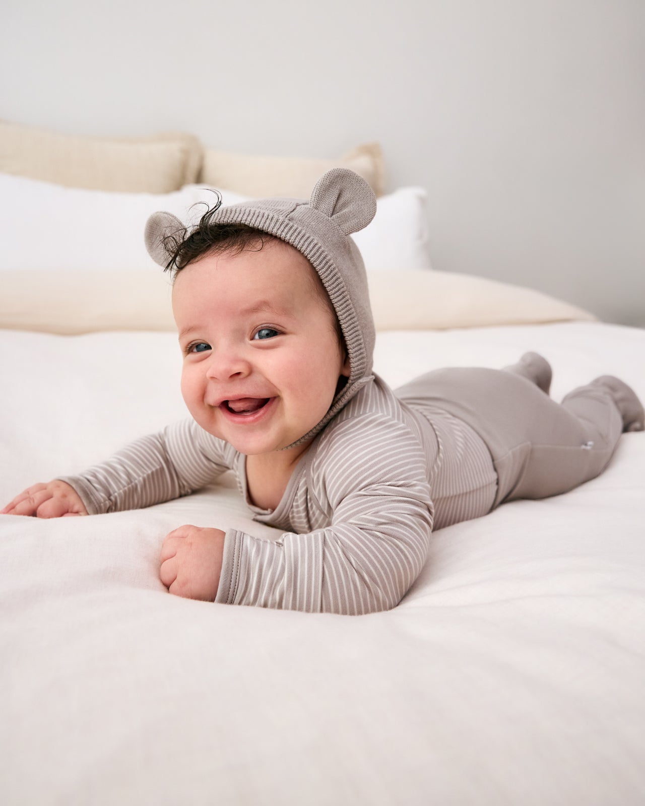 Newborn on his tummy wearing the Dove Gray Bear Bonnet