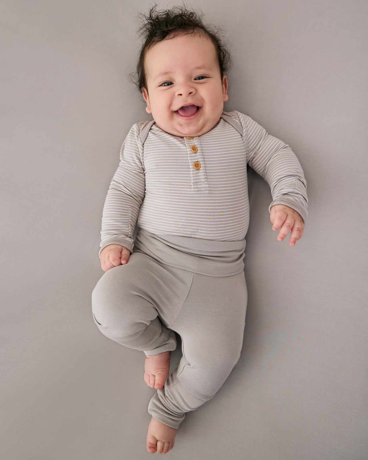 Aerial view of baby wearing the Dove Gray Fold-Over Legging with a matching striped henley bodysuit