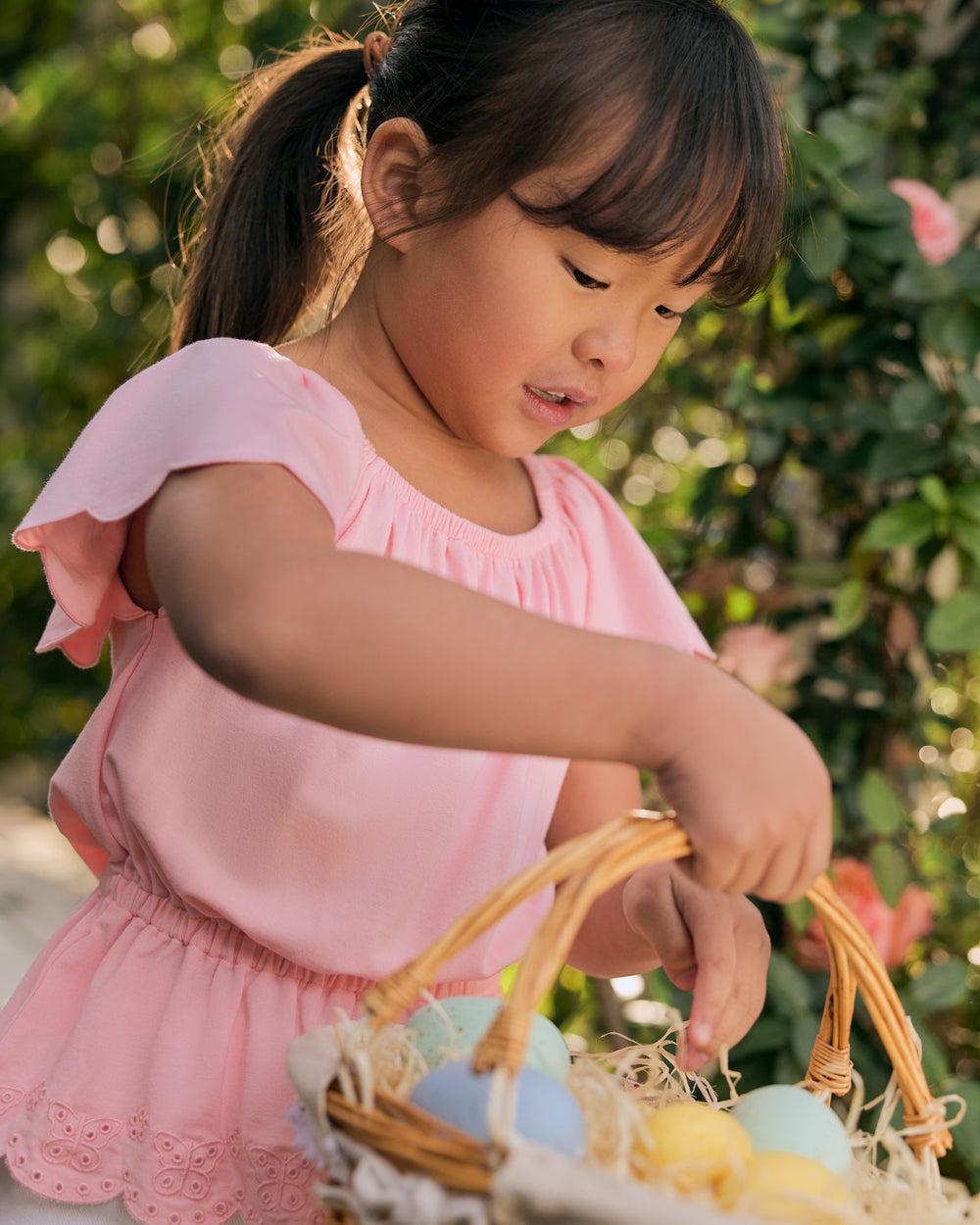 Girl wearing the Soft Coral Puff Sleeve Eyelet Top collection Easter eggs