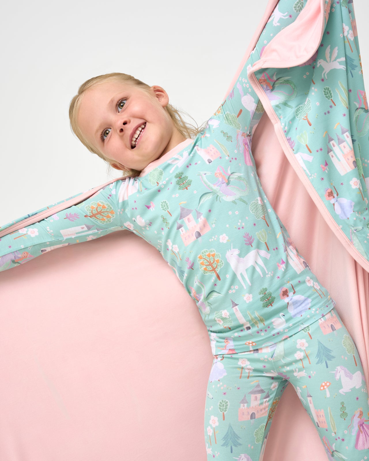 Girl wearing the Enchanted Fairytale Two-Piece Pajama Set holding up the matching cloud blanket