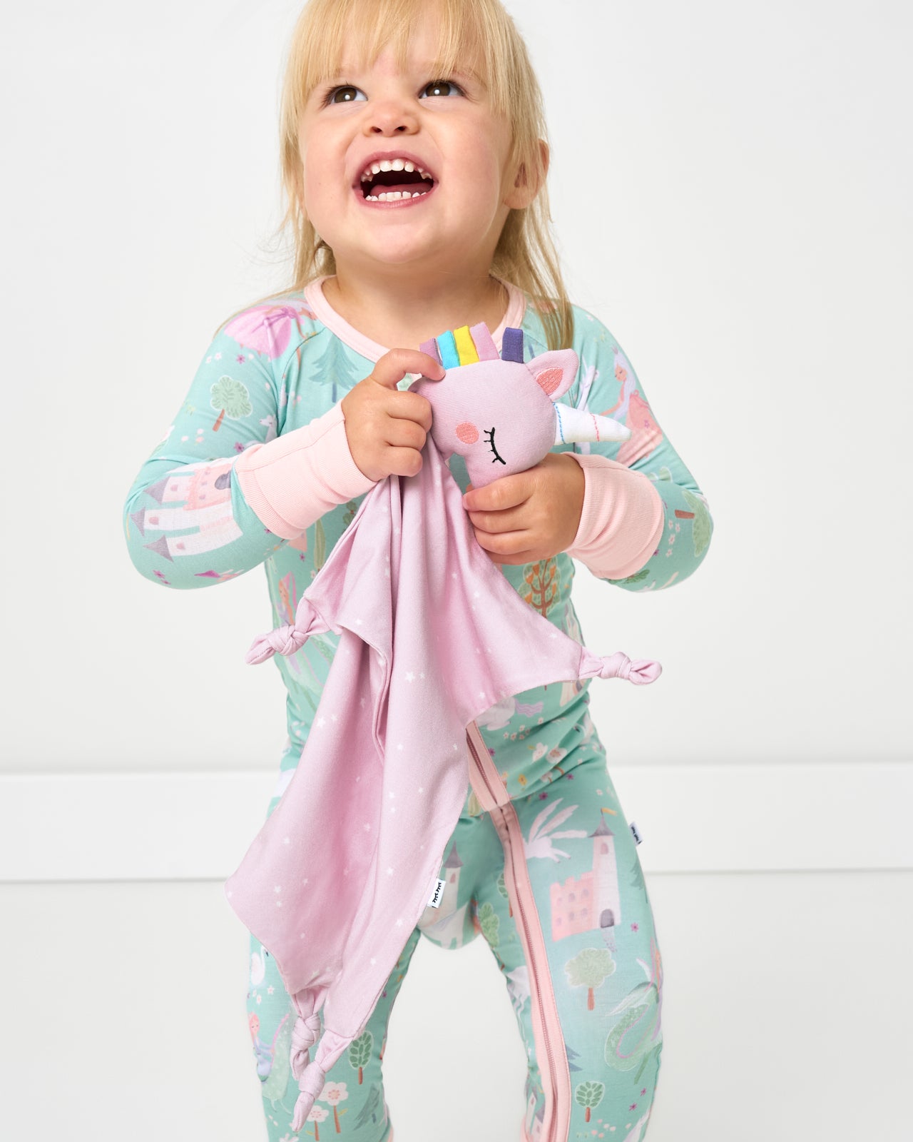 Toddler holding the Sienna the Unicorn Sleepyhead Lovey