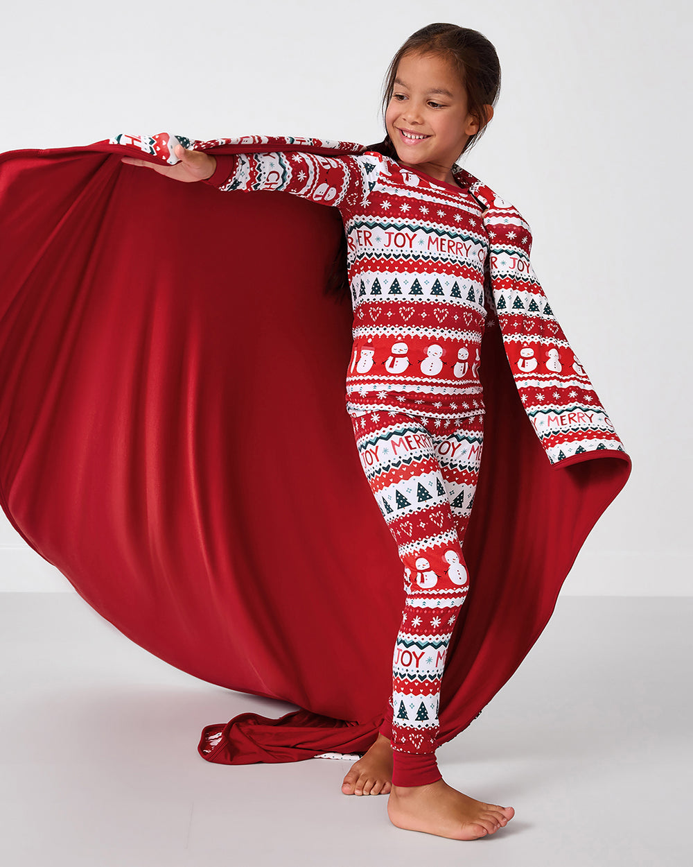 Child holding up the Festive Fair Isle Large Cloud Blanket® showing the solid red side