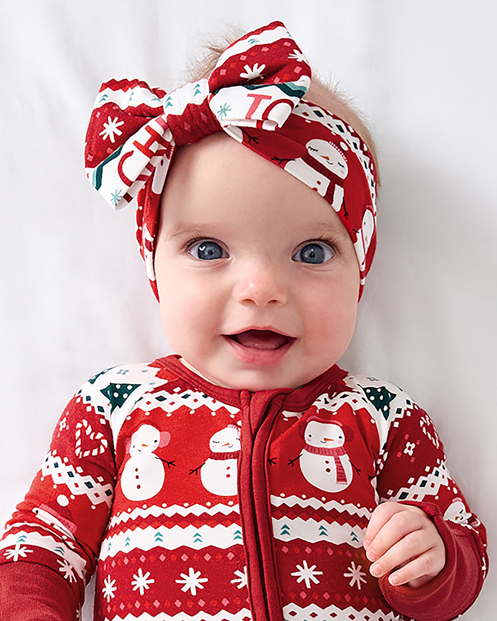 Baby wearing the Festive Fair Isle Luxe Bow Headband and matching zippy pajama