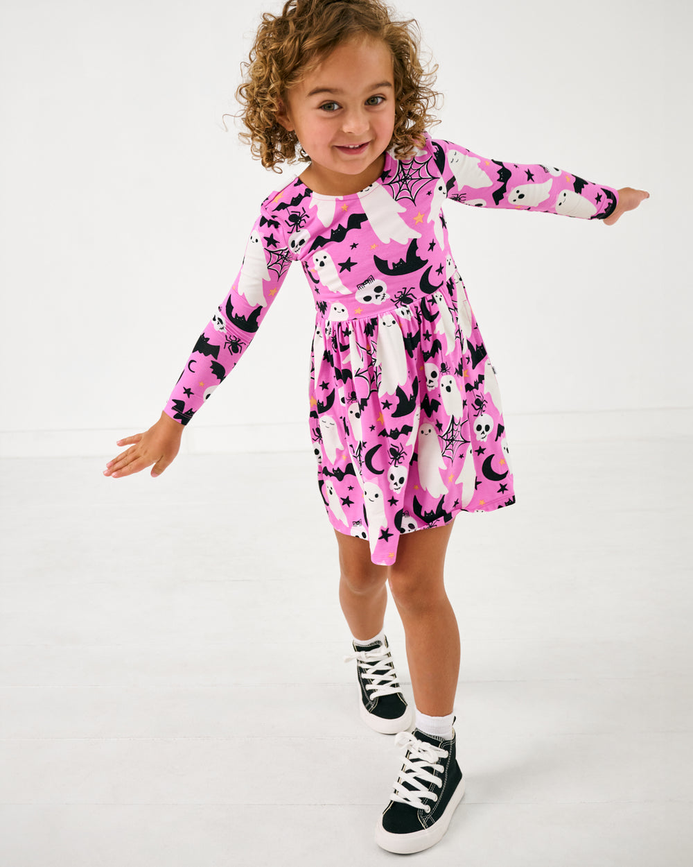 Posing girl wearing the Pink Frightful Friends Bow Back Skater Dress