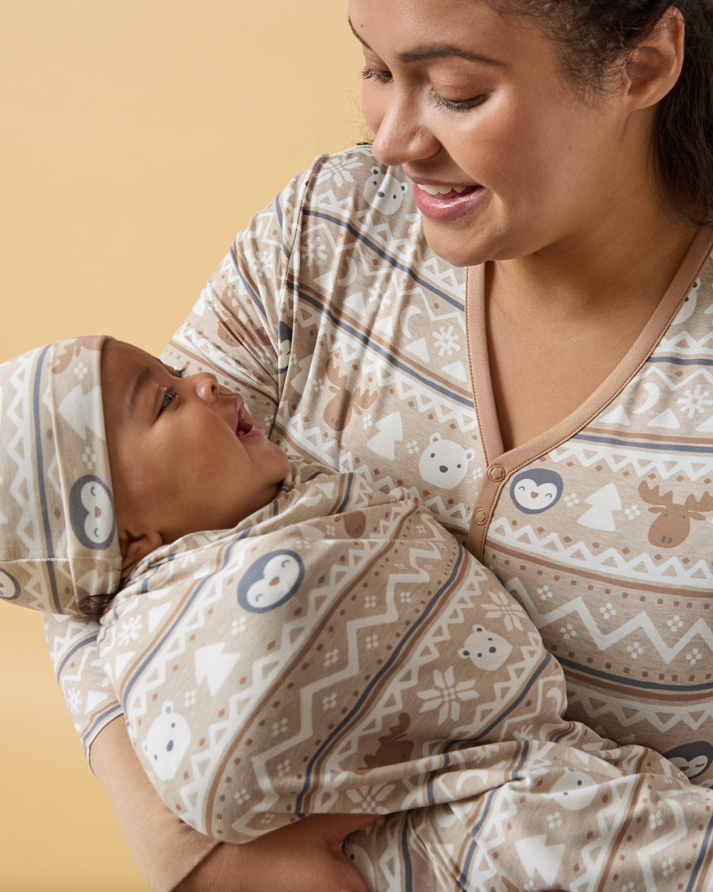 Alternate mother holding baby wearing the Frosty Fair Isle Swaddle & Hat Seton a yellow background
