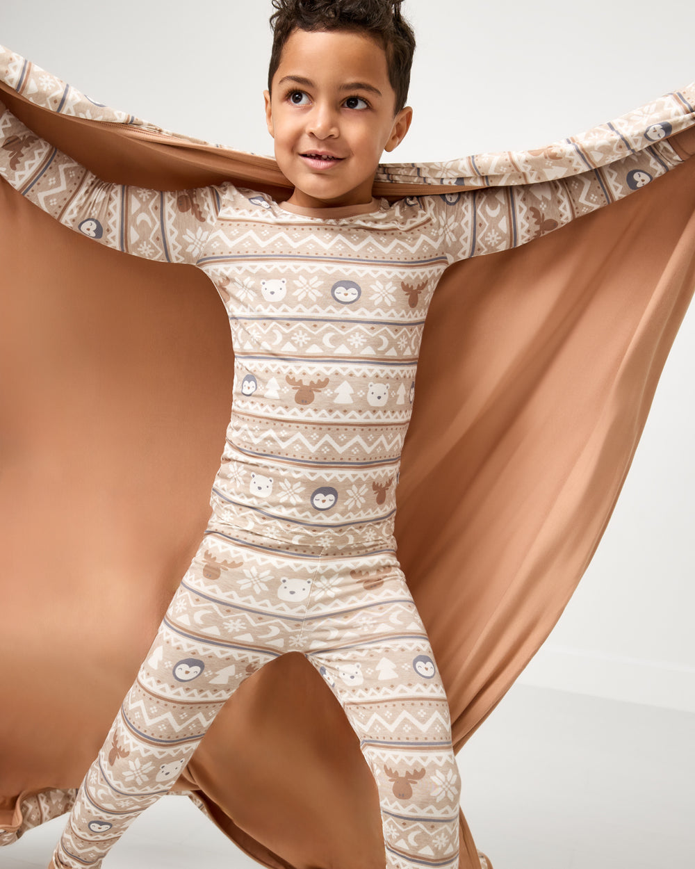 Boy holding up the Frosty Fair Isle Large Cloud Blanket® showing the solid tan side
