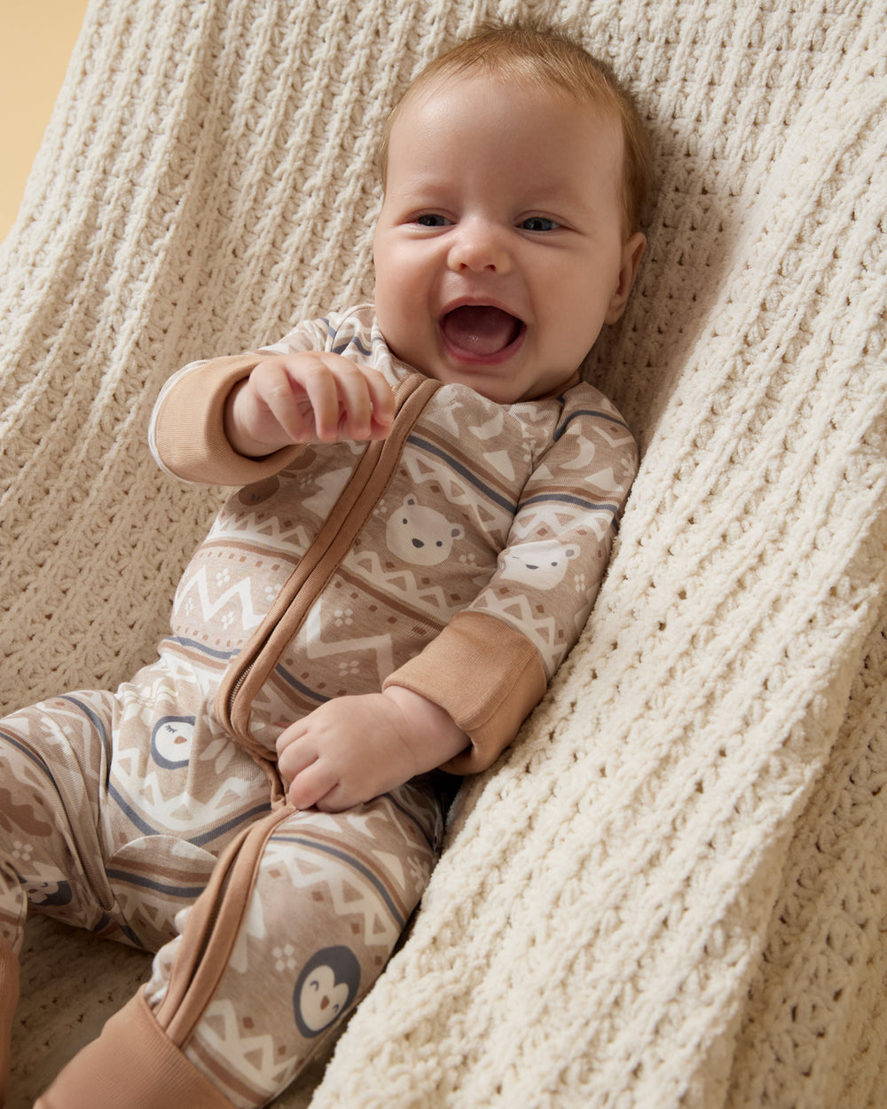Baby sitting on a knit blanket wearing the Frosty Fair Isle Zippy