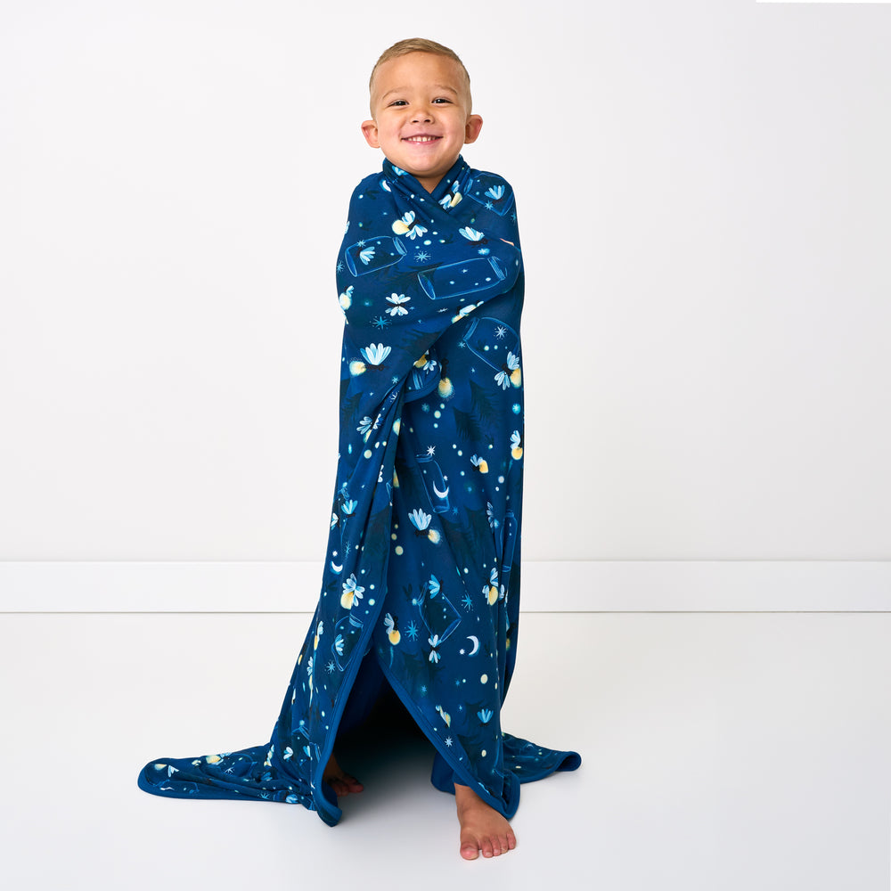 Standing child wrapped in the Firefly Glow Large Cloud Blanket®