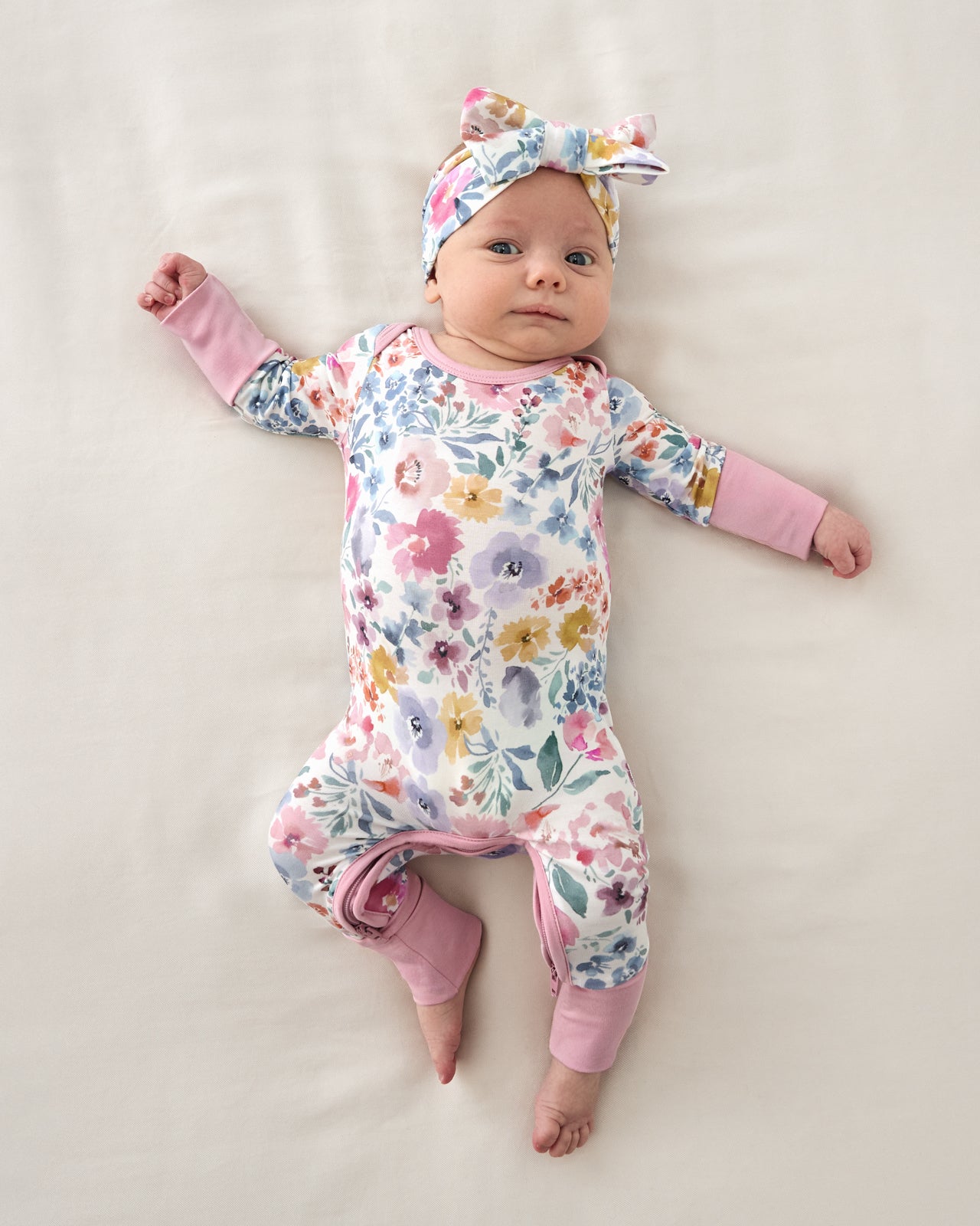 Aerial view of newborn wearing the Tiny Blooms Crescent Zippy and Bow