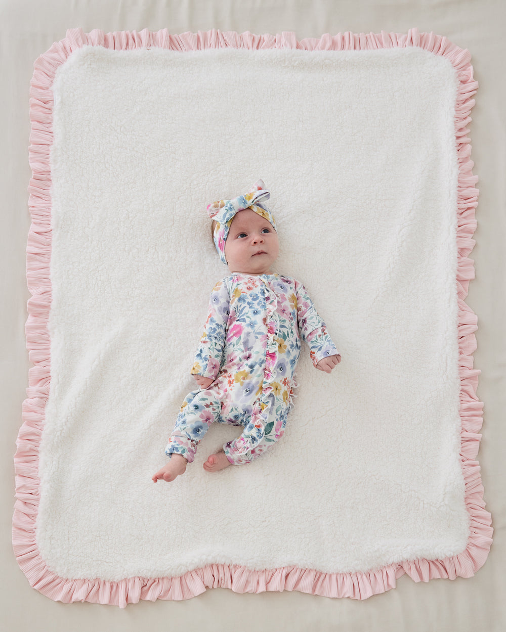 Aerial view of newborn laying on the sherpa side of the Prima Pink Ribbed Ruffle Mini Cloud Blanket®