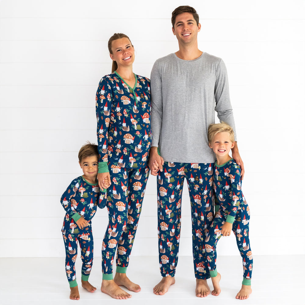 Family of four wearing the Forest Gnomes print. Male model is wearing the Forest Gnomes Men's Pajama Pant and female model is in the Forest Gnomes Women's Pajama Pant and Top. Both children are wearing the Forest Gnomes Two-piece Pajama Set