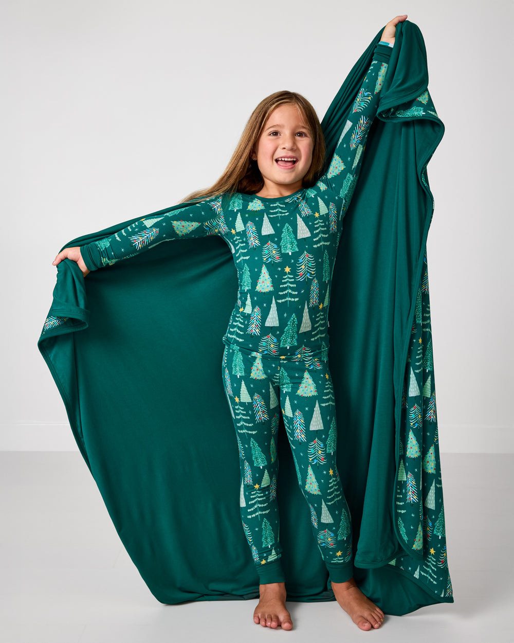 Standing girl holding up the Twinkling Trees Large Cloud Blanket® showing the solid green side