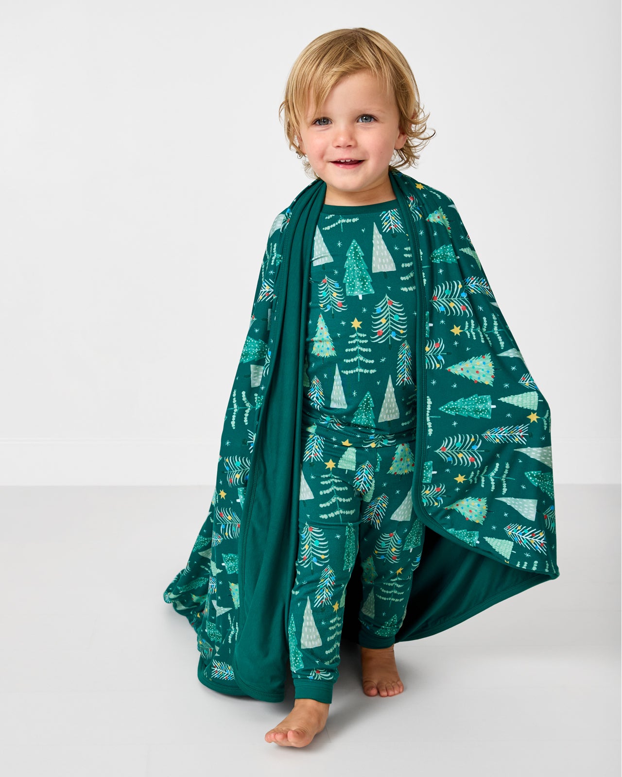 Standing boy wrapped in the Twinkling Trees Large Cloud Blanket®