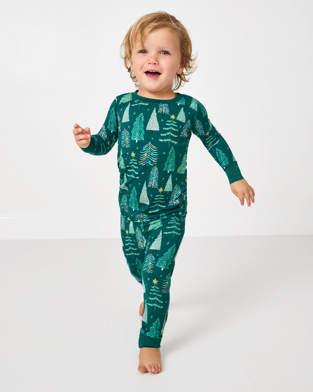 Walking child wearing the Twinkling Trees Two-Piece Pajama Set