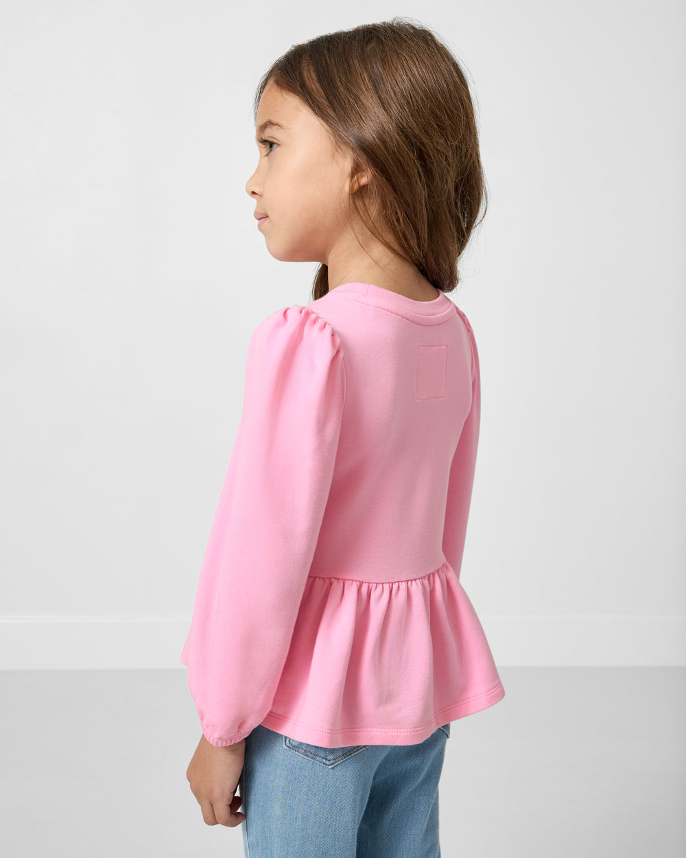 Back view of girl wearing the Gumball Pink Puff Sleeve Peplum Top