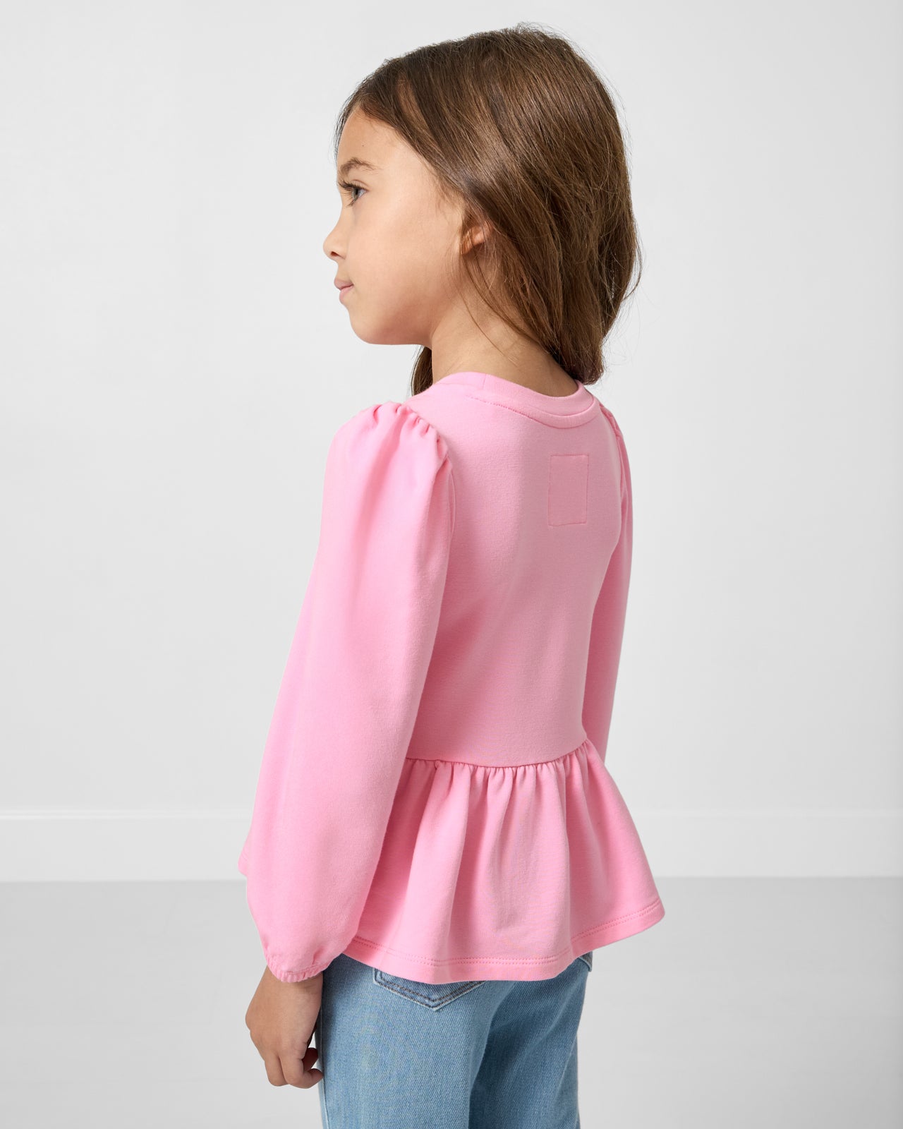 Back view of girl wearing the Gumball Pink Puff Sleeve Peplum Top