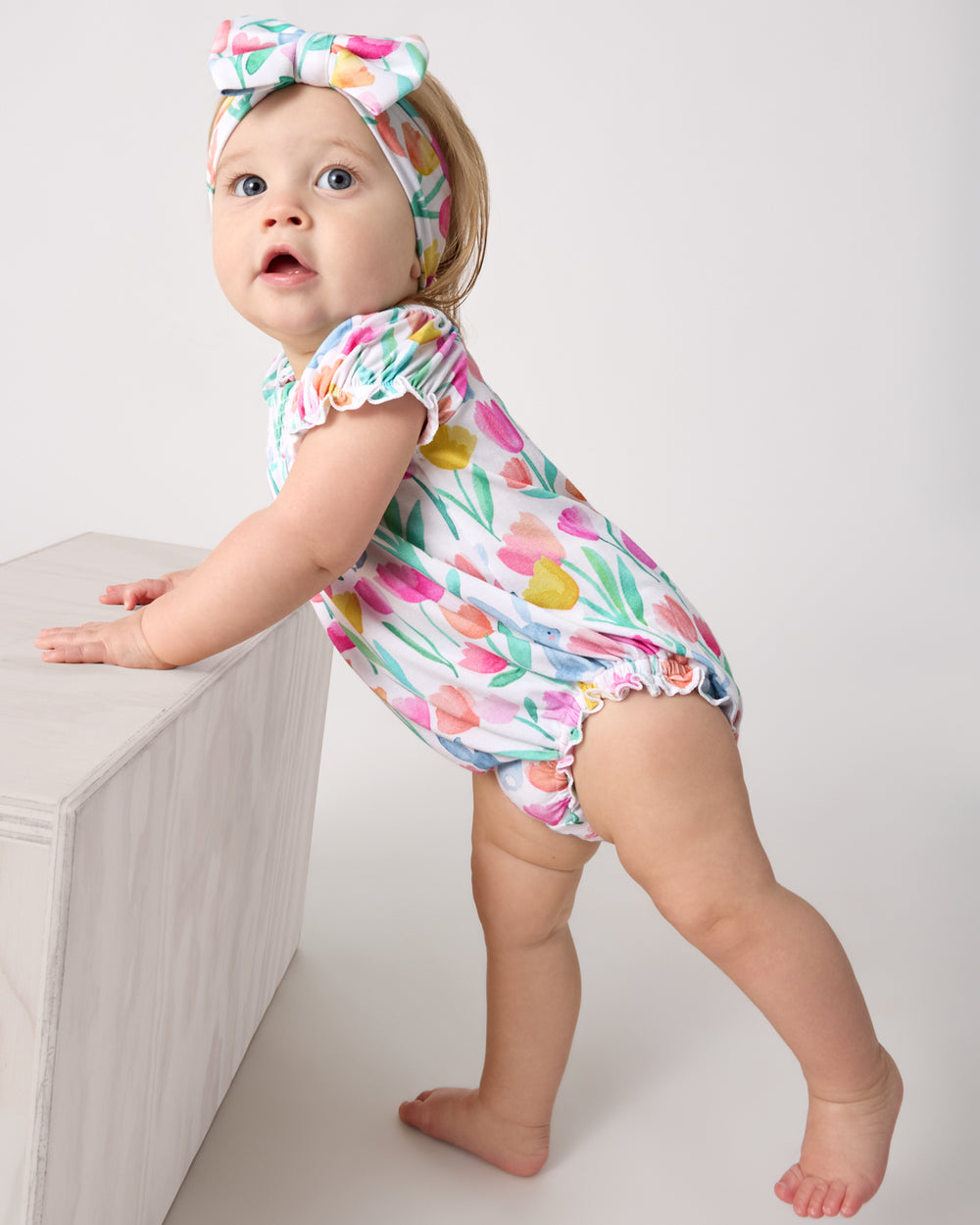 Baby wearing the Garden Hop Smocked Bubble Romper and Luxe Bow Headband