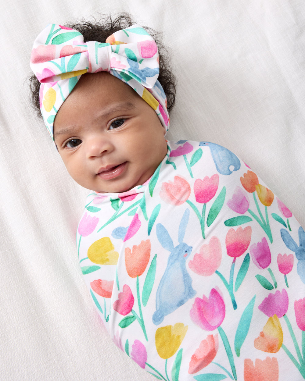 Close up of alternate baby wearing the Garden Hop Swaddle & Luxe Bow Headband Set