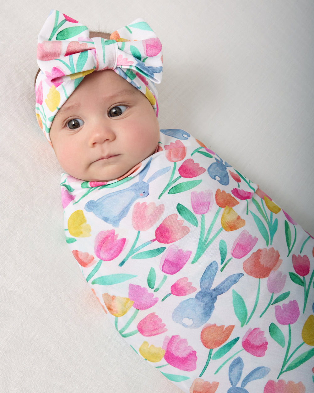 Close up of baby in the Garden Hop Swaddle & Luxe Bow Headband Set