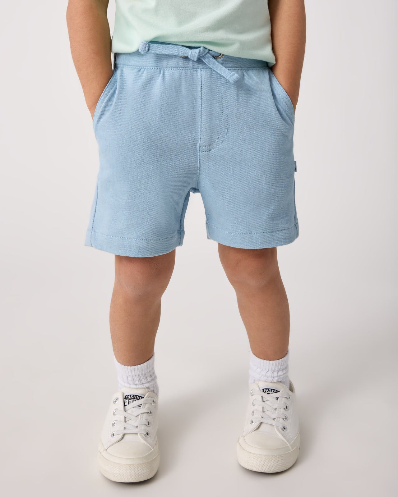 Child wearing the Gentle Blue Chino Shorts with white sneakers
