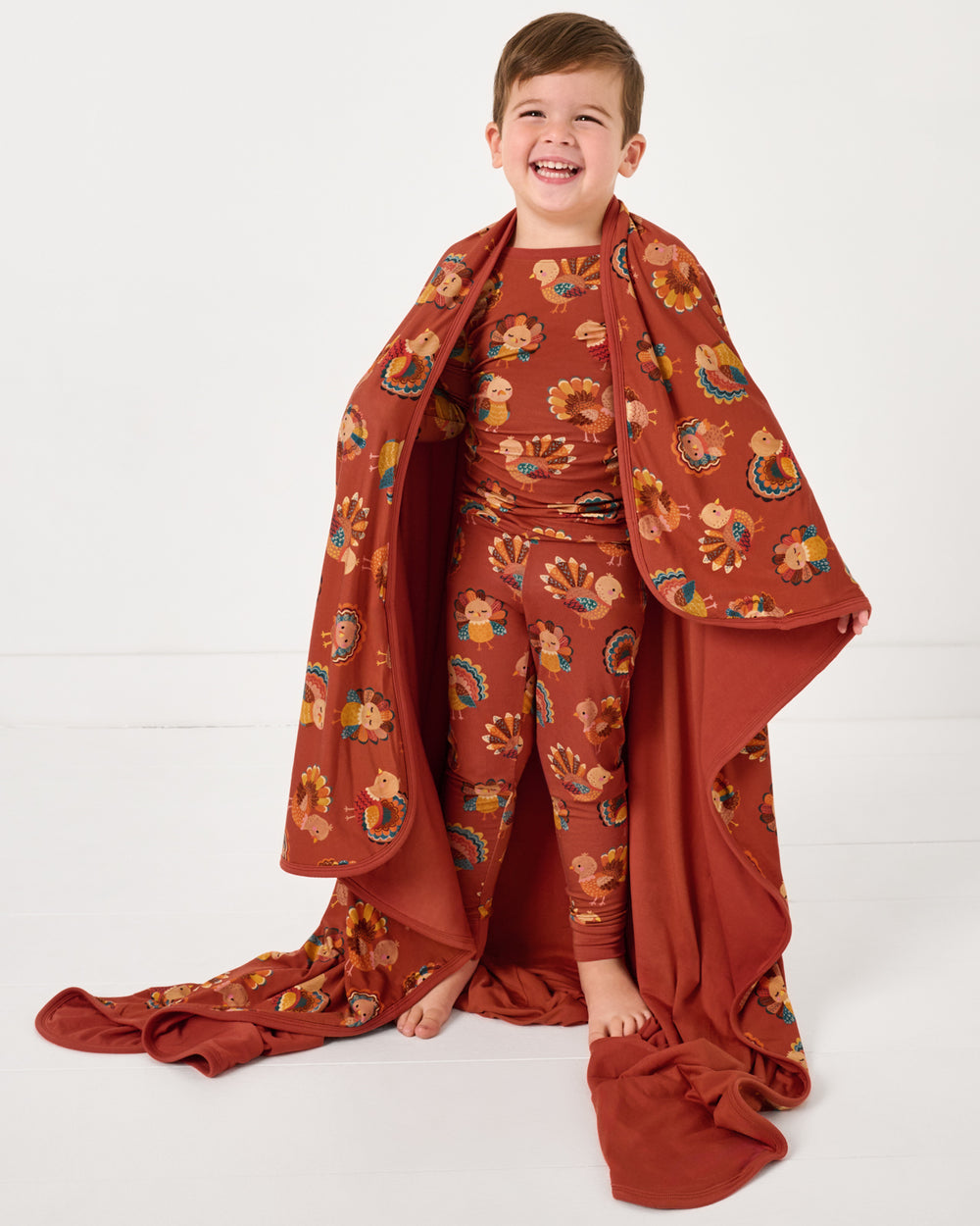 Standing boy wrapped in the Grateful Gobbles Large Cloud Blanket®