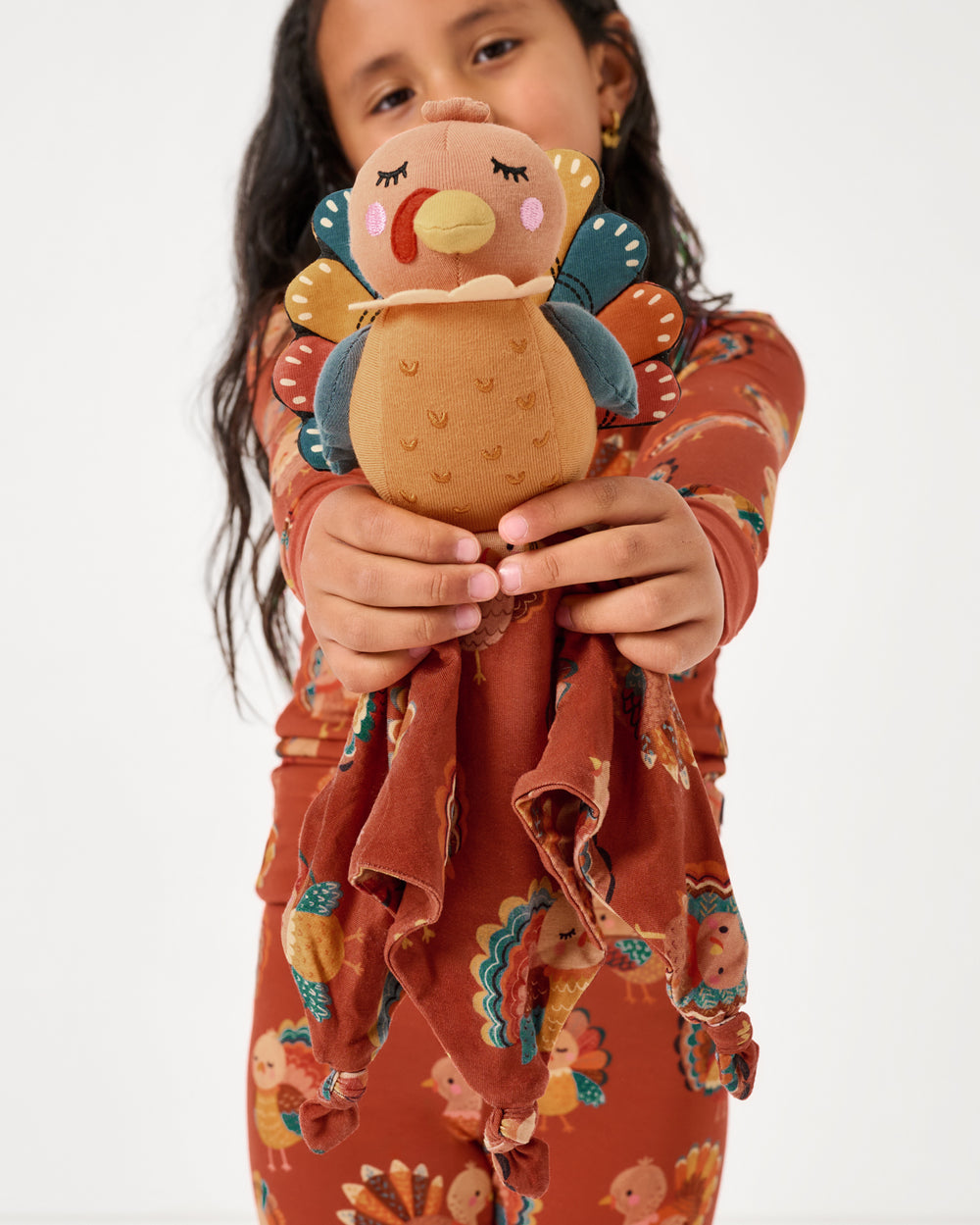 Child holding up the Tom the Turkey Sleepyhead Lovey