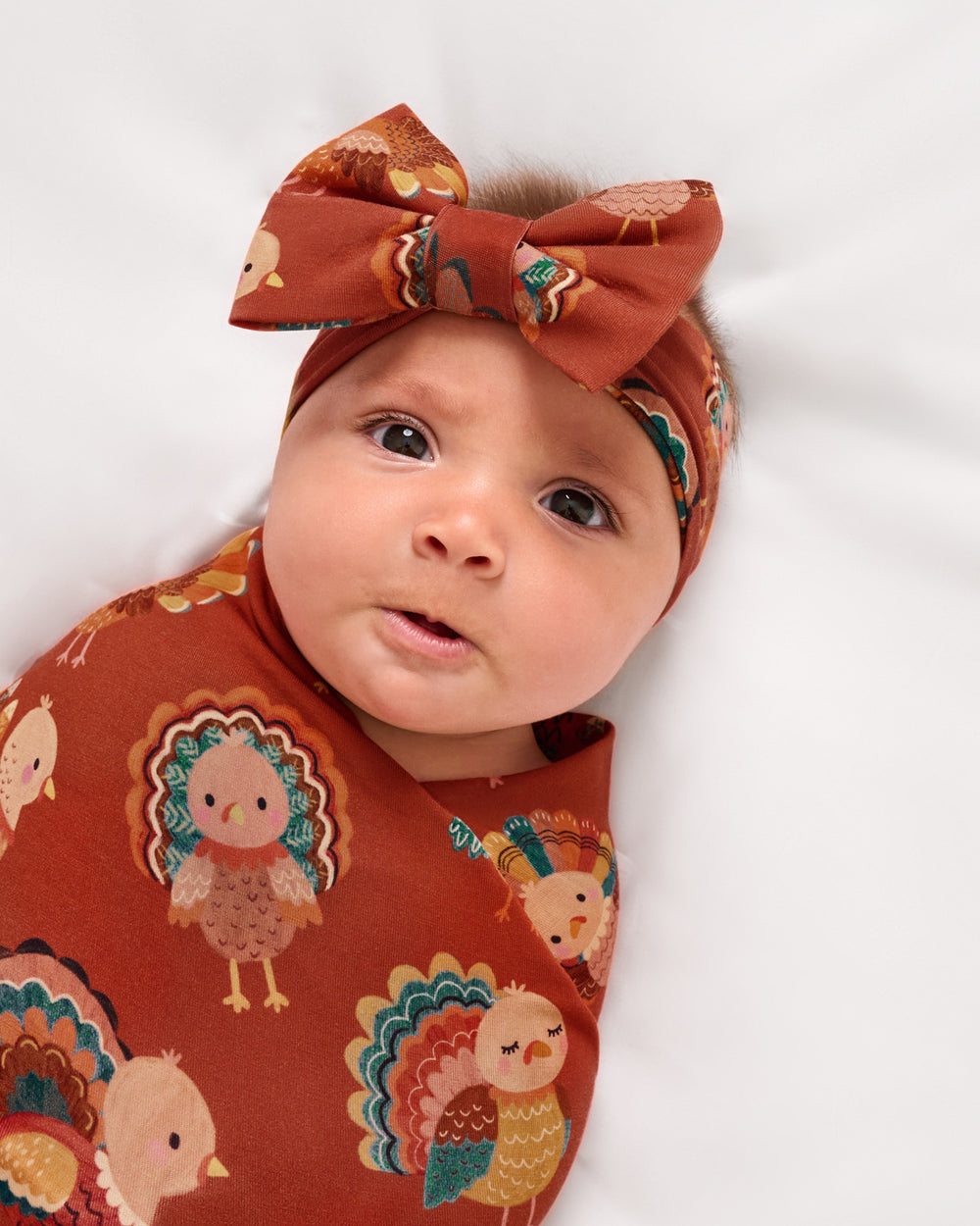 Close up of baby wearing the Grateful Gobbles Swaddle & Luxe Bow Headband Set