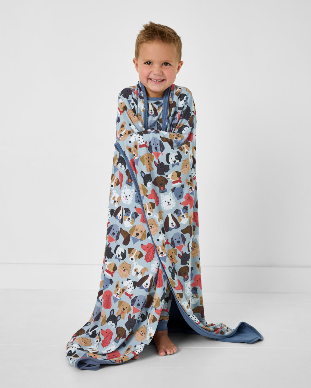 Standing boy wrapped in the Gray Puppy Parade Large Cloud Blanket®