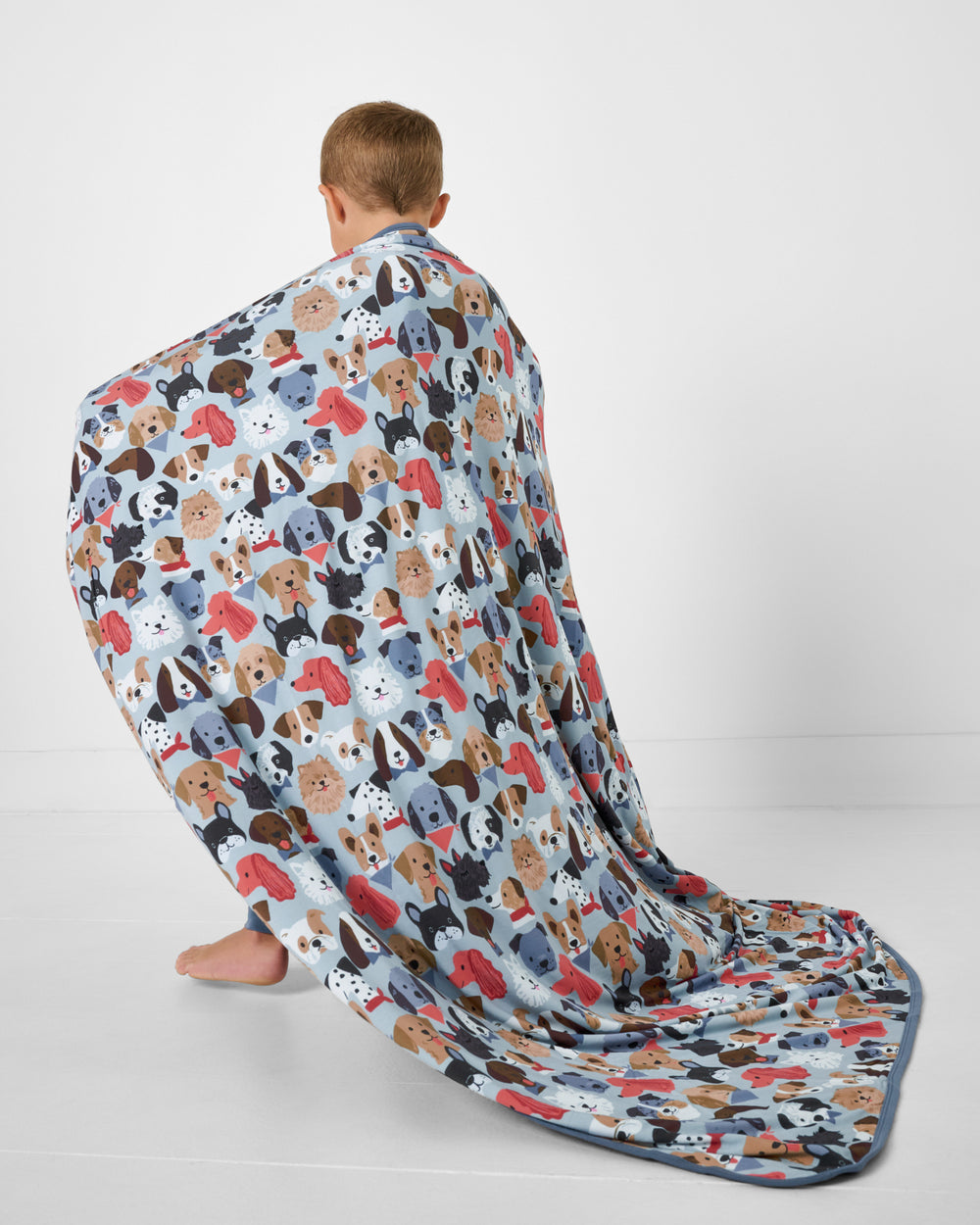 Boy wrapped in the Gray Puppy Parade Large Cloud Blanket® on a white background