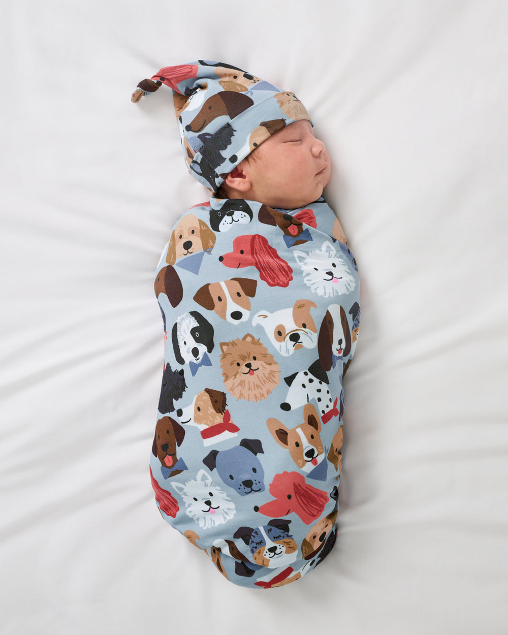 Baby wearing the Gray Puppy Parade Swaddle & Hat Set