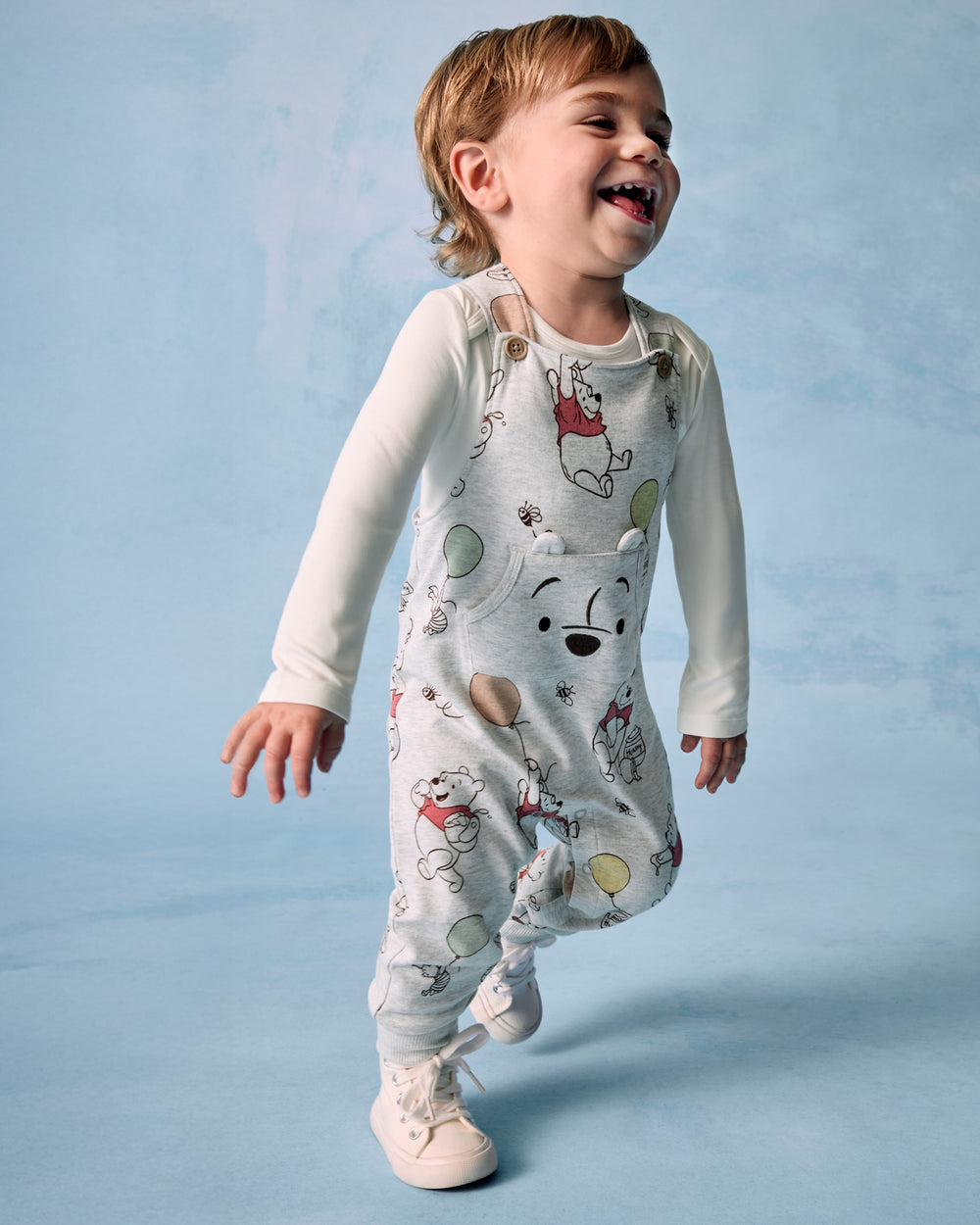 Boy wearing the Disney Up, Up and Away Overall on a blue background