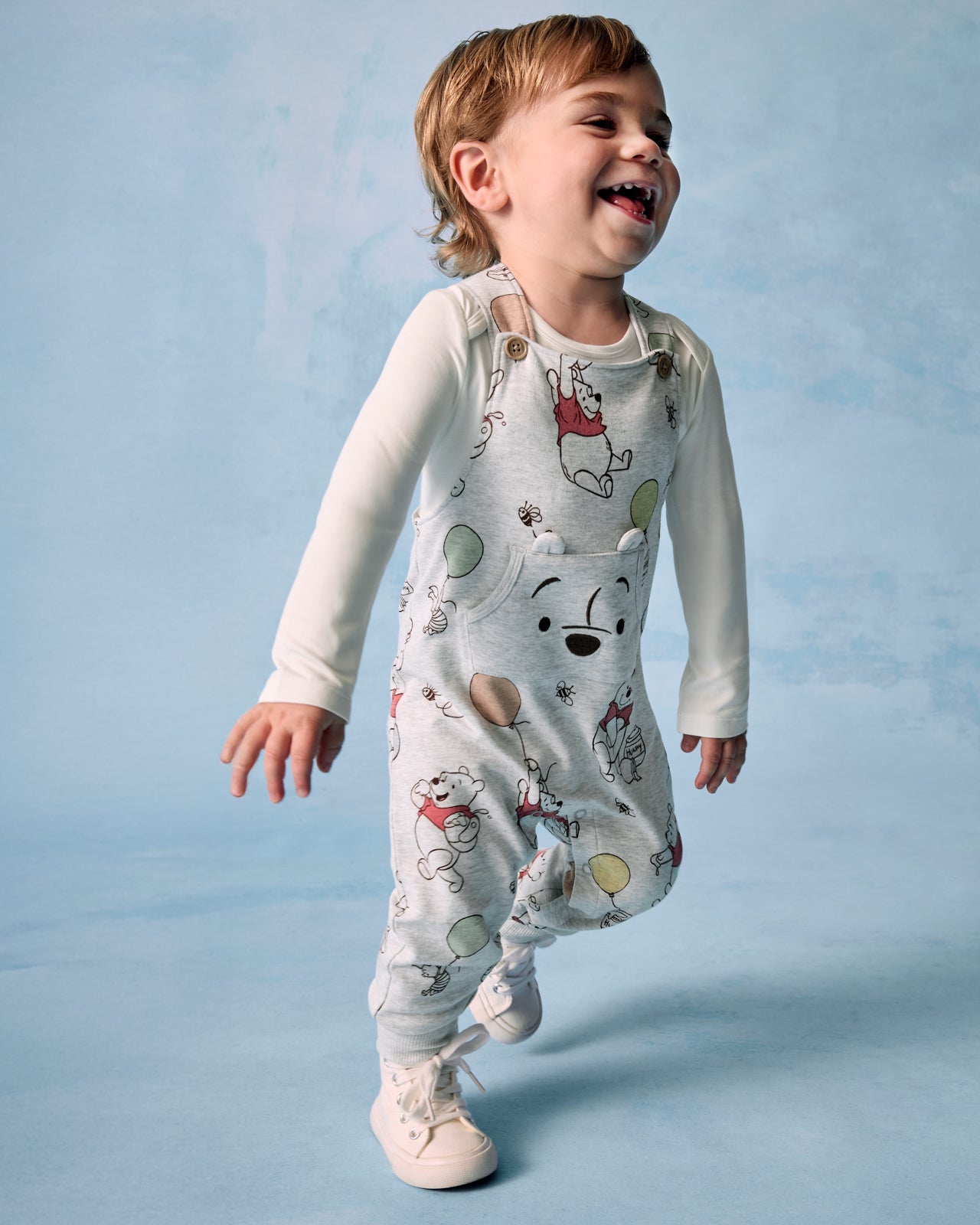 Boy wearing the Disney Up, Up and Away Overall on a blue background