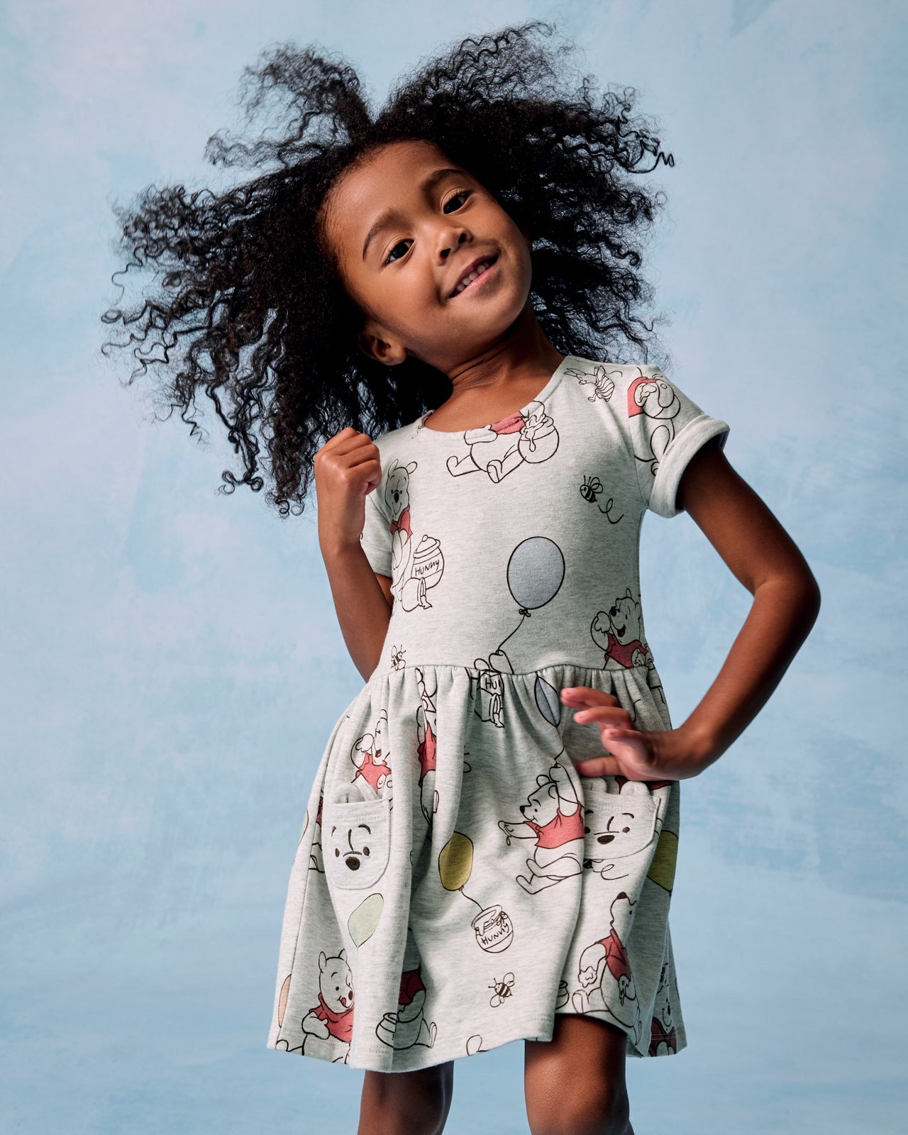 Girl wearing the Disney Up, Up and Away Patch Pocket Dress on a blue background