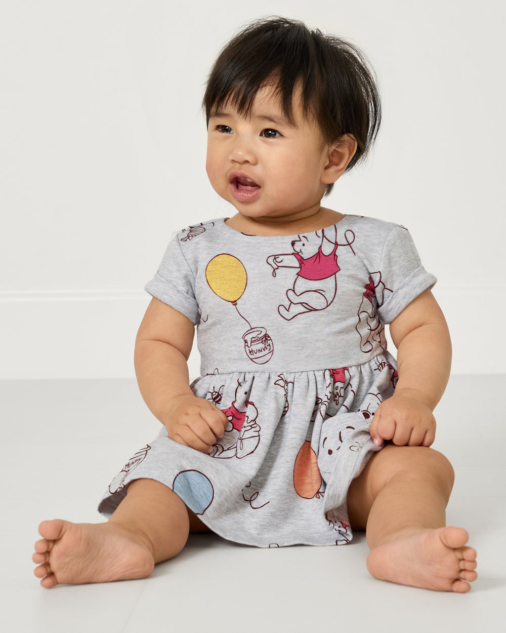 Sitting baby wearing the Disney Up, Up and Away Patch Pocket Dress with Bloomer
