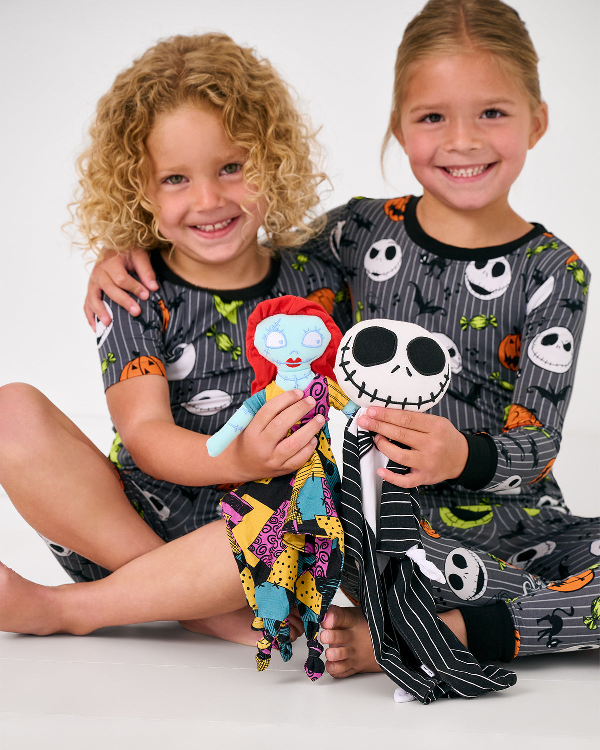 Two children holding up halloween themed loveys