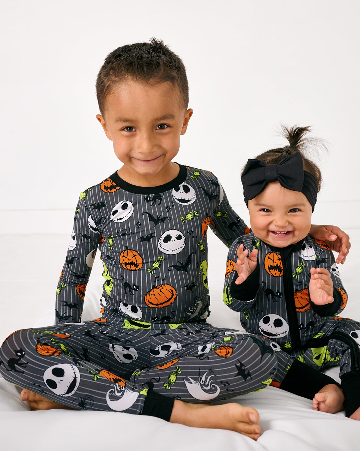 Two sitting children wearing matching Disney The Nightmare Before Christmas pajamas
