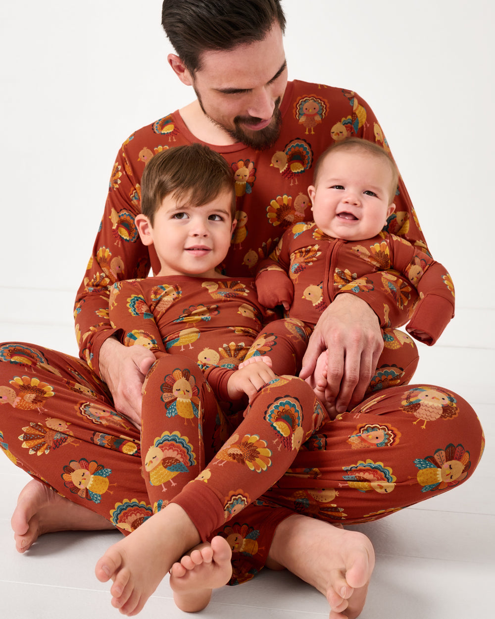 Father and two kids wearing matching Grateful Gobbles bamboo Thanksgiving pajamas