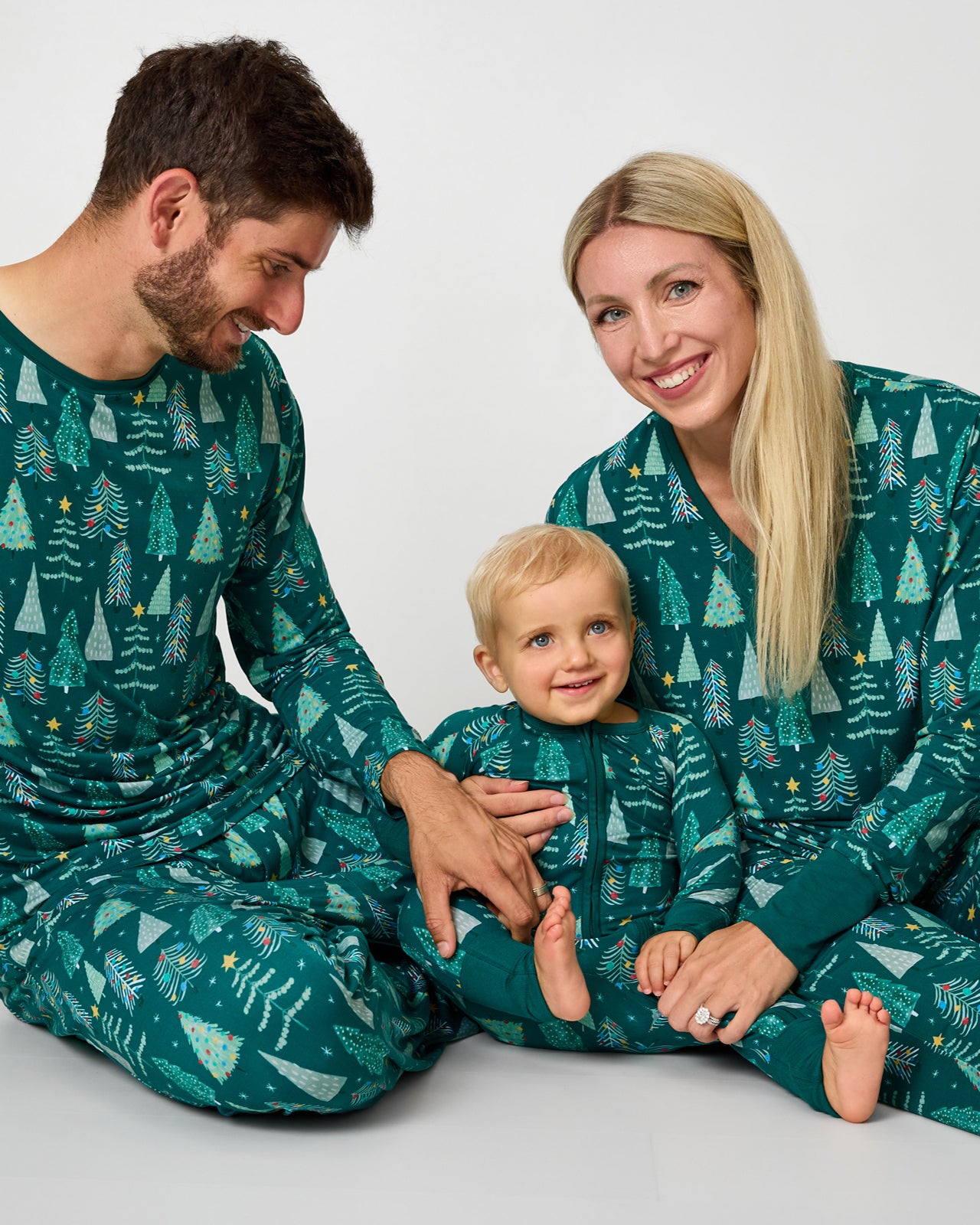 Family of three wearing matching Twinkling Trees holiday pajamas