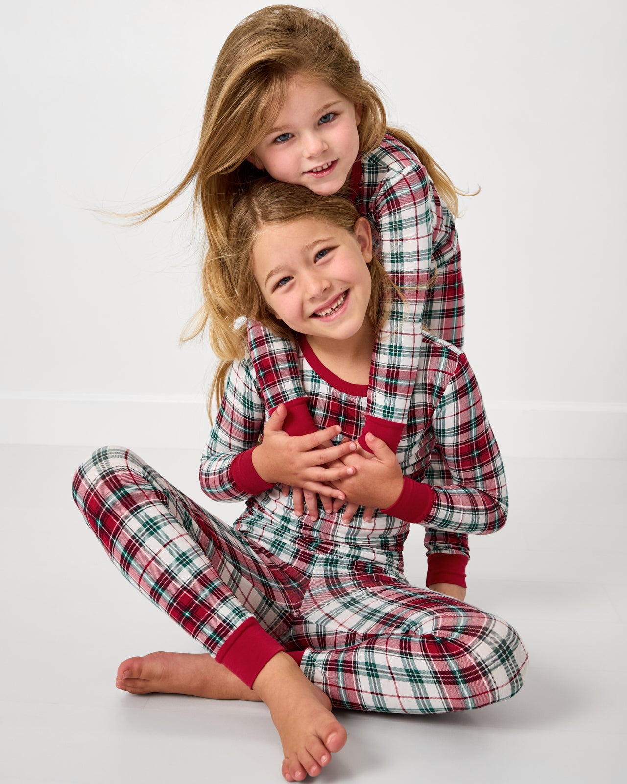 Two children wearing the Holly Plaid Holiday themed Two-Piece Pajama Set