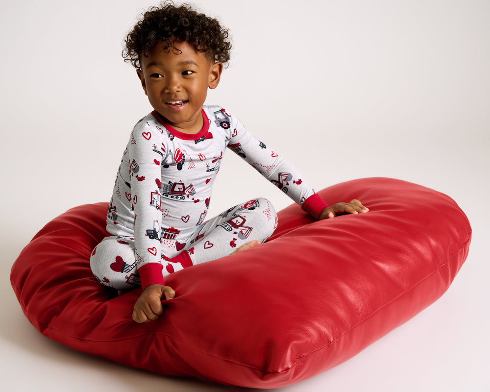 Child sitting on a heart shaped cushion wearing the Loads of Love Two-Piece Pajama Set
