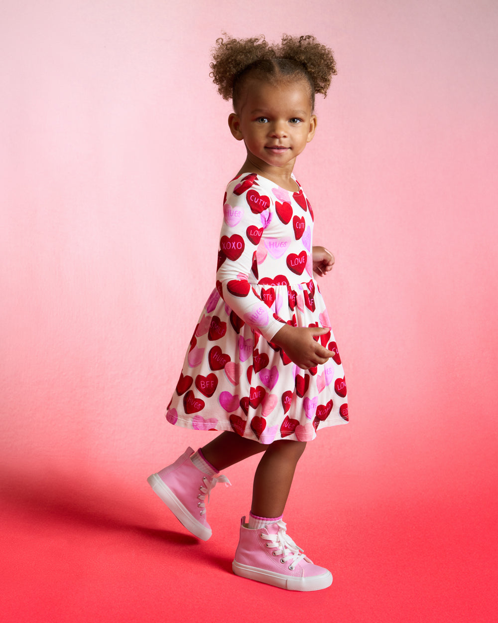 Girl wearing the Candy Cuties Bow Back Dress with Bodysuit on a red background