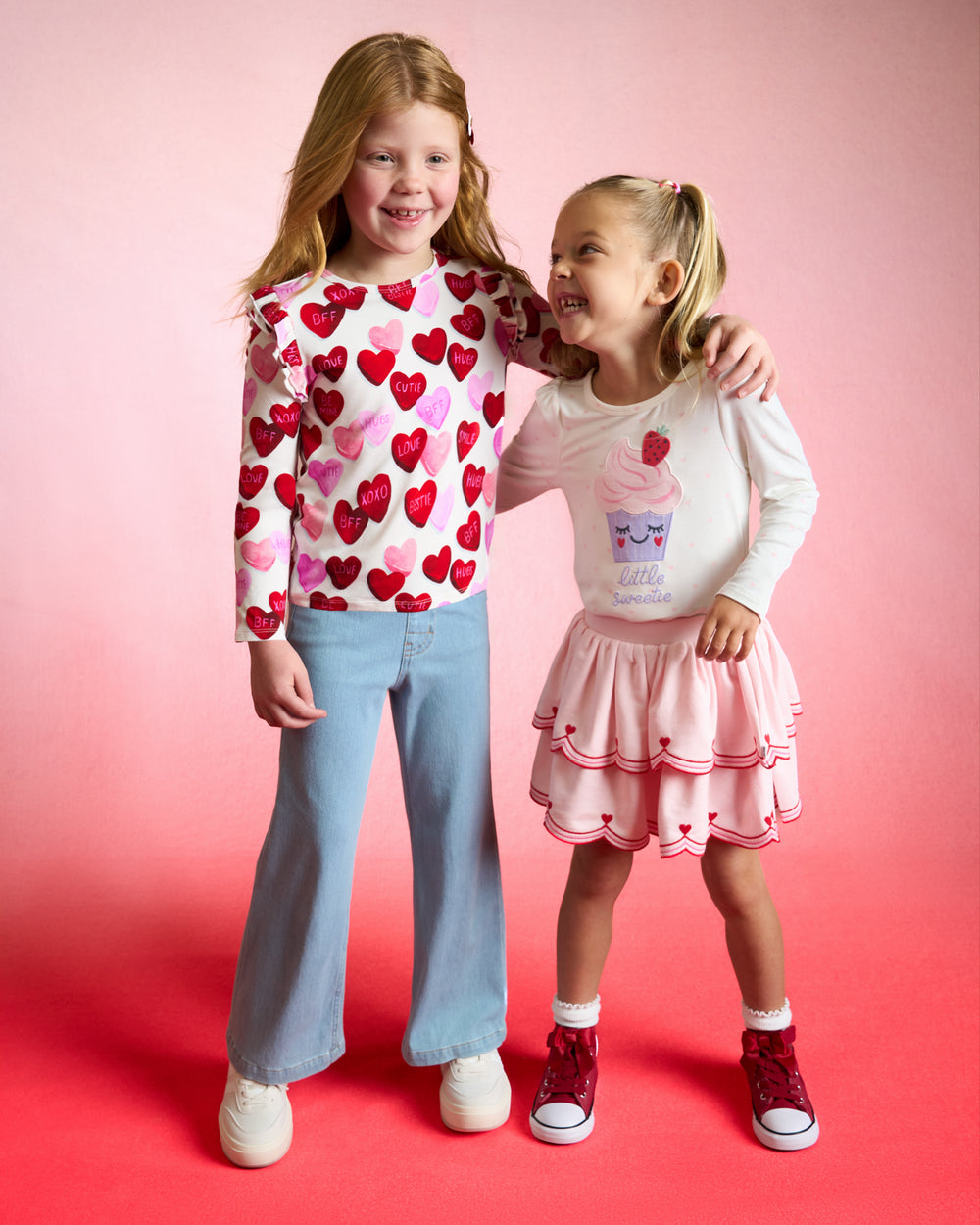 Two girls wearing Valentines Day styles on a red background