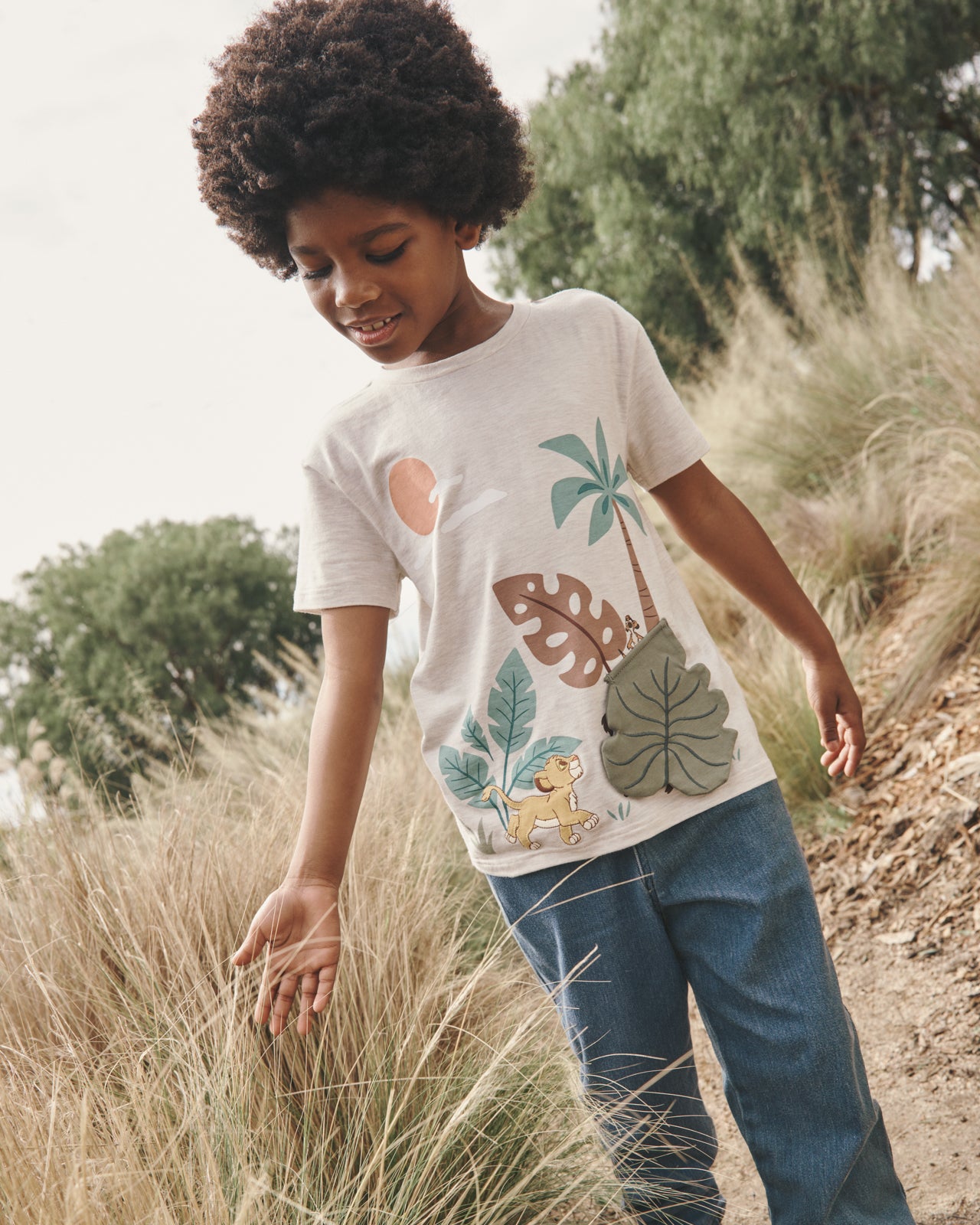Boy wearing the Disney Safari Hideaway Relaxed Tee with a grassy background
