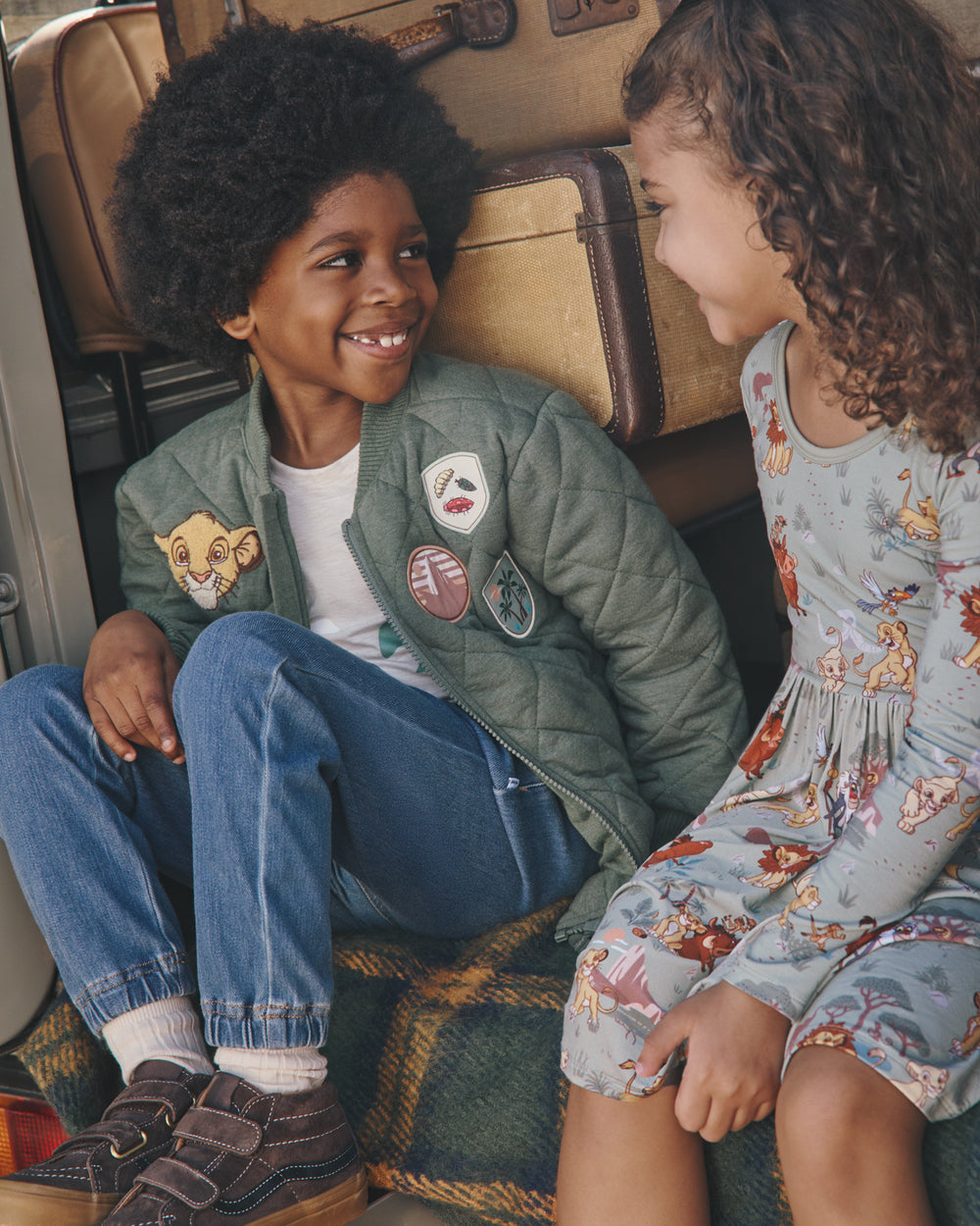 Two children wearing Lion King play styles with a safari themed background