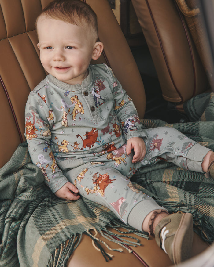 Toddler wearing the Disney Simba's Safari Henley Romper on a leather seat