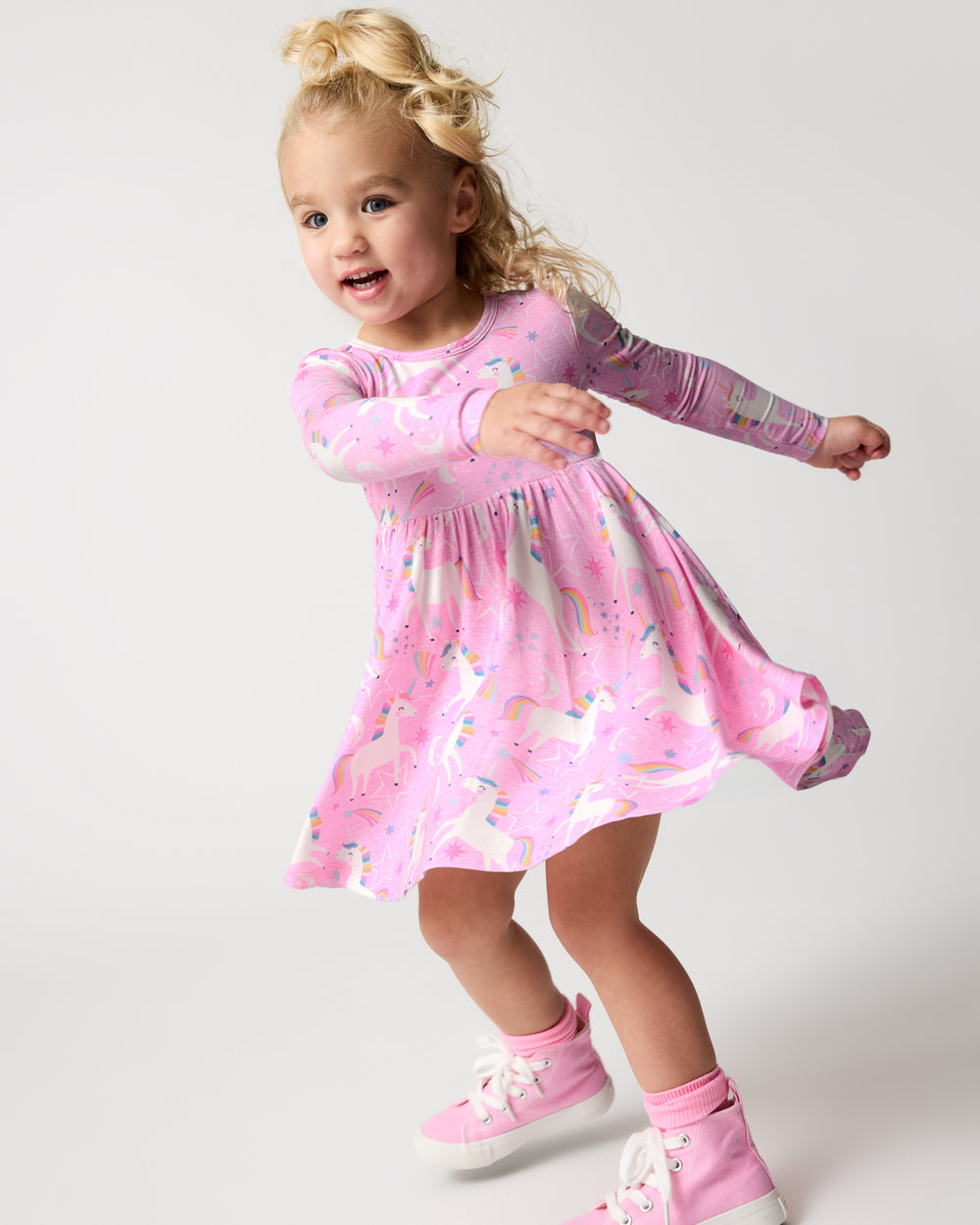 Girl in motion wearing the Unicorn Dance Twirl Dress with pink sneakers