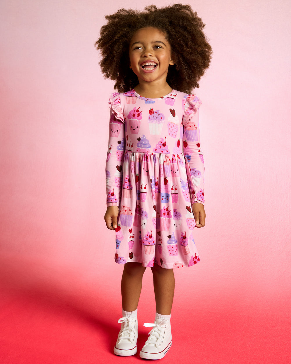 Girl wearing the Cupcake Kisses Flutter Skater Dress on a red background