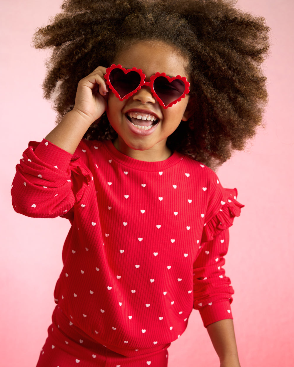 Child wearing the Little Love Ribbed Flutter Crewneck with heart shaped sunglasses