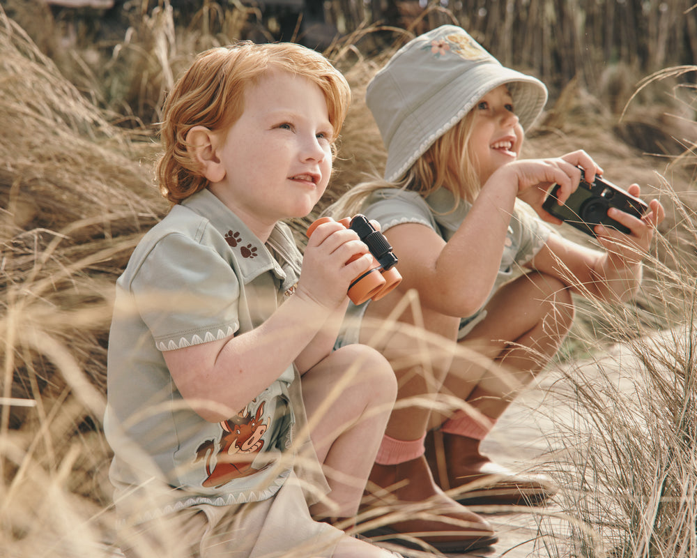 Two children wearing Lion King play styles with a grassy background
